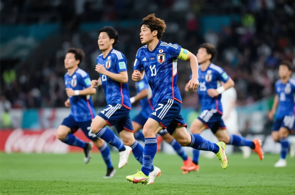 日本国家男子足球队在赛场上奔跑，蓝色球衣
